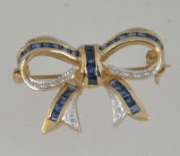 A 9ct gold sapphire and diamond brooch in the form of a bow.