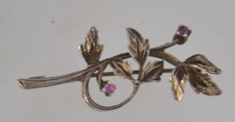 A silver and ruby brooch in the form of a flower.