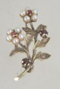 A vintage 1970's / 1980's silver brooch set with see pearls and garnet stones.