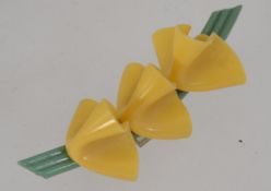 A 1930's Art Deco Bakelite green bar brooch with three yellow lilies and safety pin clasp.