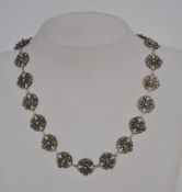 A silver necklace with filigree and granulated floral links. Tests silver. Measures 15 inches.