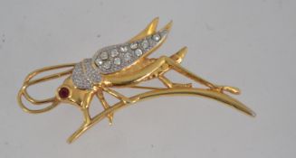 A large vintage figural brooch pin in the form of a grasshopper with rhinestone set wings and eye