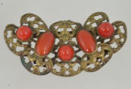 A 1920's Czech brooch of brass filigree work having faux coral glass cabochons with loop clasp.
