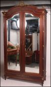 An early 20th century French armoire wardrobe raised on turned legs with double bevelled mirror