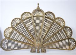 A 20th Century brass metamorphic peacock firescreen having eight fan out leaves with a Griffin base