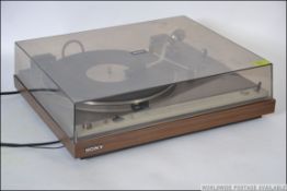 A retro Sony PS 5550 belt drive record player having a teak effect base with a smoked perspex lid