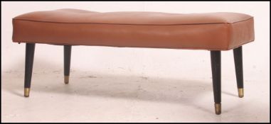 A 1950's brown vinyl upholstered low footstool raised on ebonised tapering dansette legs.