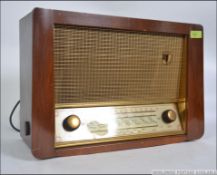 A vintage wooden cased valve cased HMV valve radio with display and dials to the front and HMV logo