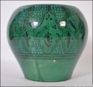 An Islamic pottery vase decorated with green and red flowers amongst blue borders.