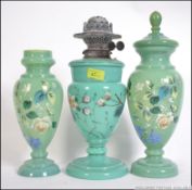 A late 19th century hand painted oil lamp with two matching vases each with hand painted floral