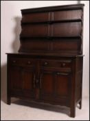 An Ercol dark Jacobean revival beech and elm dresser having cupboards and drawers to the base with