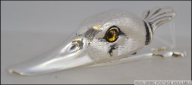 A silver plated paper clip in the form of a ducks head, with inset glass eyes. Measures: 13cms long.