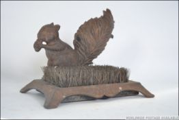 A cast metal shoe scrap in the form of a squirrel eating its nuts having an inset brush.