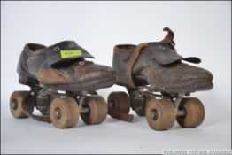 A pair of vintage mid century leather roller skates having wooden wheels to both skates L18cm