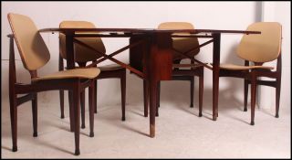 A 1950's teak wood drop leaf dining table together with a set of matching dining chairs upholstered