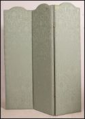 A stunning three fold dressing screen having a soft green satin covering over wooden frames with