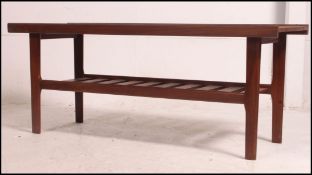 A mid century Danish influence teak coffee table raised on tapered angled supports with magazine