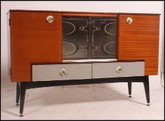 A retro teak and two tone cabinet having sliding glass doors with half moon handles raised on