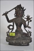 An early bronze Chinese figurine of a robed deity seated with sword and raised over socle plinth