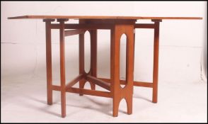 A 1970's G-Pan / Cintique retro teak wood drop leaf dining table being raised on pierced supports.