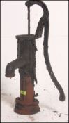 A Victorian / 20th century cast iron water pump being ebonised with a scroll handle.
