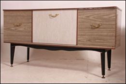 A 1950's retro melamine sideboard raised on tapered supports with a series of cupboards and drawers