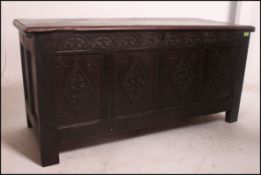 An 18th century country oak coffer chest raised on stile supports having carved fielded panels