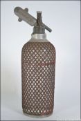 A 20th century glass and wire mesh soda syphon having an aluminum attachment marked for Sparklets.