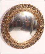 A 1950's mahogany convex wall mirror having gilt rococo frame with fish eye mirror to centre.