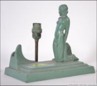 An art deco cast metal figural table lamp in the form of a kneeling nude female on stepped cast