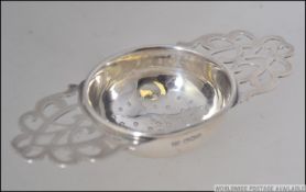 A silver hallmarked tea strainer. The pierced centre dish with fretted scrolled handles either side.