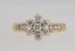 A 9ct gold and diamond ring with central diamond cluster and channel set diamond shoulders.