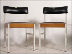 A pair of vintage / retro mid century chairs having black vinyl seats and back panels raised on
