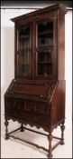 A 1920s oak Jacobean revival bureau bookcase with geometric moulded detail,