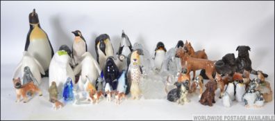 A collection of ceramic and studio glass penguins of various forms to include Bristol blue style,