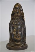 A Chinese wooden carved deity having a female bust with a praying Buddha atop both covered with a