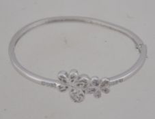 A silver and cz adorned 20th century childs christening bracelet / bangle having flower head