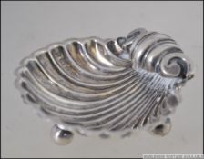 A silver hallmarked table salt in the form of an oyster shell being raised on ball feet.