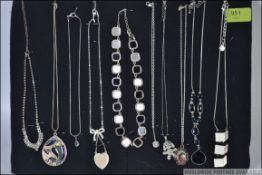 A collection of ten silver and silver metal necklaces some with pendants all mounted on a display