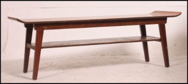 A surfboard style mid century Danish influence teak coffee table raised on tapered angled supports.