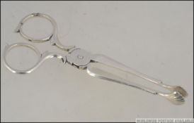 A silver hallmarked pair of sugar nips / tongs having scalloped shell pincher's.