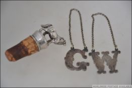 A silver (tested) metal cork bottle top adorned with figurine of a dog together with 2 white metal