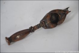 A Black Forest carved oak nutcracker in the form of a squirrel having twist handle with nut recess