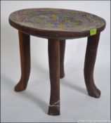 An African Tribal stool raised on 4 carved legs with circular seat and painted top with inset