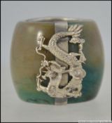 An unusual Chinese carved jade archers ring with applied central silver white metal with applied