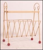 A mid century wire work painted magazine rack / canterbury having red finials with the top having