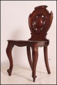 A Victorian solid mahogany hall chair with armorial carved back rest over panel seat and turned
