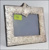 A silver hallmarked easel back picture frame having floral decoration in repose having London assay