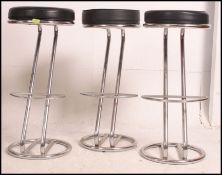 A set of 4 Black and chrome retro style bar stools with padded circular seats and tubular chrome