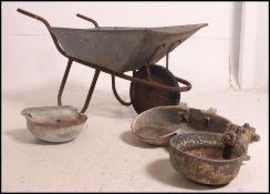 A mid 20th century galvanised wheel barrow along with three vintage cast water troughs please see